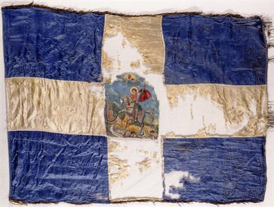 Κυανόλευκη αναμνηστική πολεμική σημαία με παράσταση του Αγίου Γεωργίου στο κέντρο του σταυρού. Προσφέρθηκε στη Μεραρχία Σμύρνης με Συνταγματάρχη τον Αλέξανδρο Μαζαράκη-Αινιάν, κατά την απελευθέρωση της πόλης το 1920.