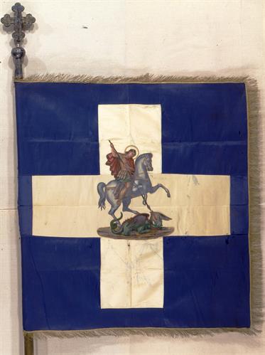 Κυανόλευκη πολεμική σημαία με παράσταση του Αγίου Γεωργίου στο κέντρο του σταυρού. Ανήκε στο στρατηγό Δημήτριο Ιωάννου.