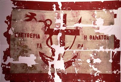 Flag of a battleship of Psara of 1821, with the symbols of Filiki Eteria, cross, anchor, spear, serpent and bird. It bears the inscription: ΕΛΕΥΘΕΡΙΑ Η ΘΑΝΑΤΟΣ – ΨΑΡΑ ( Freedom or Death – Psara). This flag was raised on the battleship “Psara” during the N