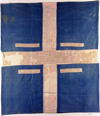 Σημαία του αγωνιστή της Δυτικής Ελλάδος Γεωργίου Κ. Βελή, που έλαβε μέρος στα επαναστατικά κινήματα των Αγράφων και του Βάλτου. Κυανή με λευκό σταυρό και επιγραφές.