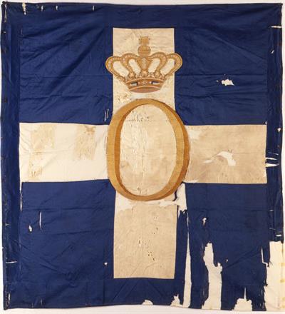 Σημαία του Διοικητηρίου της Πάτρας. Κυανή με λευκό σταυρό. Φέρει το αρχικό του ονόματος του βασιλιά Όθωνα στο κέντρο και στέμμα. Στη β&#039; όψη φέρει βαυαρικό θυρεό με λευκούς και κυανούς ρόμβους.