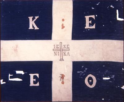 Κυανή σημαία με λευκό σταυρό, που χρησιμοποιήθηκε στο ολοκαύτωμα της Μονής Αρκαδίου το 1866. Ανήκε στο Γεώργιο Δασκαλάκη και τη διέσωσε μετά το θάνατό του η μητέρα του, Χαρίκλεια. Φέρει τα αρχικά: Κ (Κρήτη) Ε (Ένωση) Ε (Ελευθερία) ή Θ (Θάνατος).