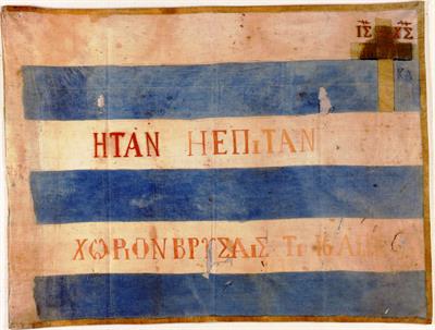 Σημαία της Κρητικής Επανάστασης του 1878 του Νικολάου Ανδρεάκη. Κυανόλευκη με σταυρό και κόκκινες επιγραφές.