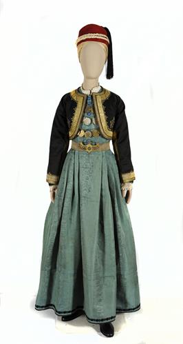 Γιορτινή αστική φορεσιά από την Καστοριά. Αποτελείται από μεταξωτό πουκάμισο, πολύπτυχο πράσινο φουστάνι και κοντό μαύρο γιλέκο. Τη μέση δένει χροσοΰφαντη ζώνη και το κεφάλι καλύπτει κόκκινο φεσάκι, 19ος αι.