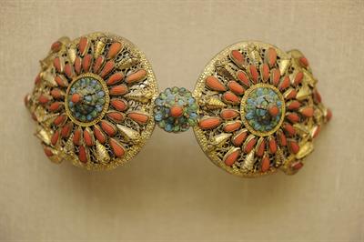 Gilded buckle from Safranbolu, Pontus. It consists of curved round cast plaques with stylized crowns on the edges. It bears corals, flowers made of enamel, mastoid edges and stylized bees.