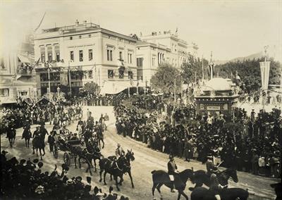 Οι άμαξες με τους βασιλείς της Ελλάδας και της Αγγλίας κατευθύνονται προς το Παναθηναϊκό Στάδιο για τους Ολυμπιακούς Αγώνες 1906. Πλατεία Συντάγματος στη συμβολή με την οδό Σταδίου.