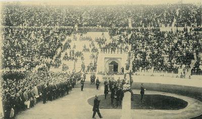 Ο Διάδοχος Κωνσταντίνος κηρύσσει την έναρξη των Ολυμπιακών Αγώνων 1906 στο Παναθηναϊκό Στάδιο. Στην πρώτη σειρά της κερκίδας η κυβέρνηση του Γ. Θεοτόκη. Επιστολικό δελτάριο.