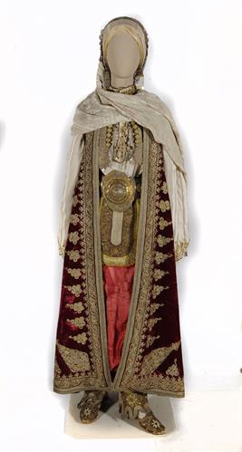 Bridal and festal costume from Argyrokastro, Northern Epirus. It consists of a tunic with gold embroidery, a red silk breeches, a gold girdle, a short gold-decorated waistcoat, a long sleeveless open overcoat (&quot;pirpiri&quot;) and velvet slippers with gold embr