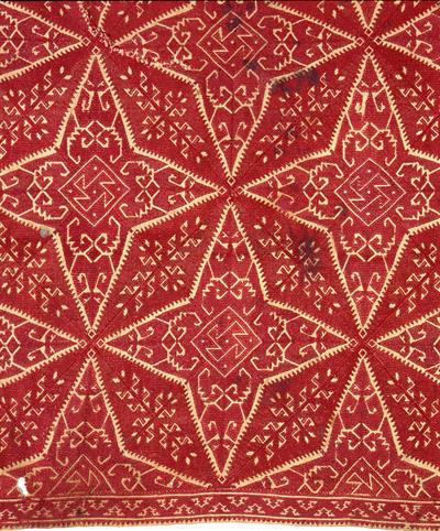 Κάλυμμα από τη Νάξο διακοσμημένο με σχηματοποιημένα φύλλα δουλεμένα με κόκκινο μετάξι.